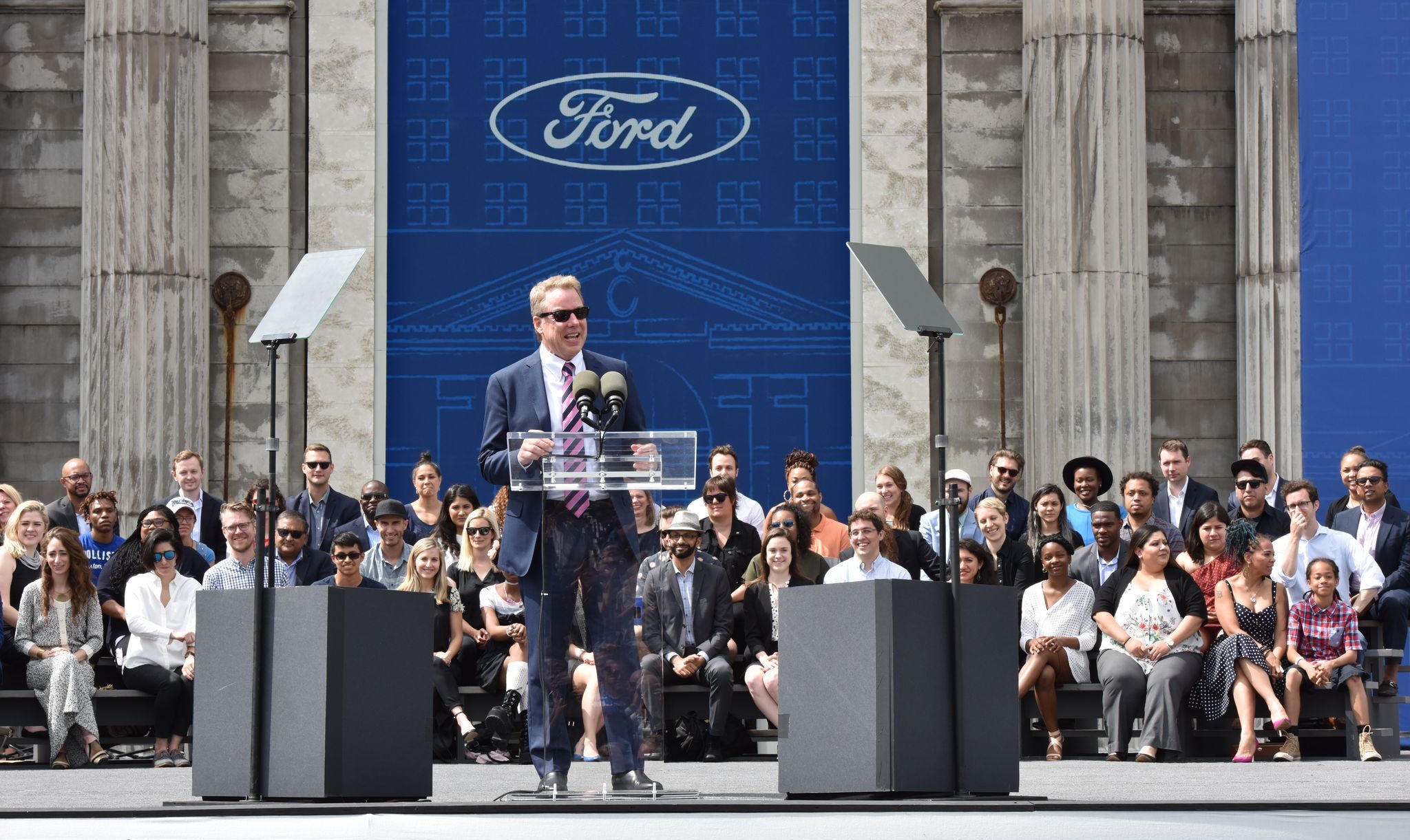 Bill Ford speaking in front of Michigan Central to an audience.