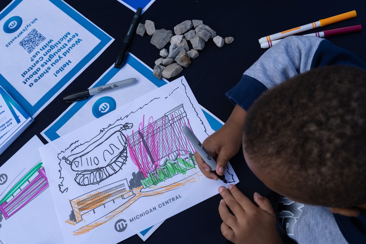 A child colors a photo of the Station on a Michigan Central coloring sheet.